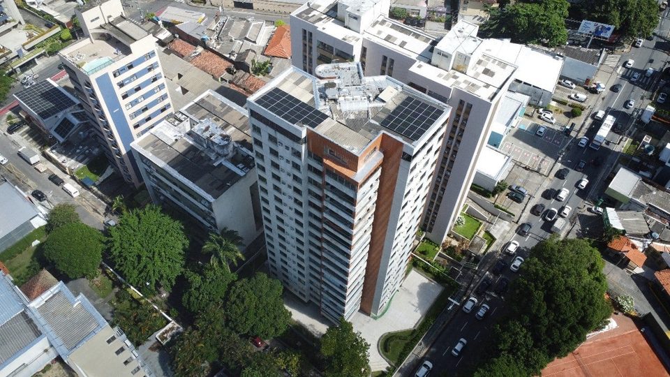 Torre residencial laranja e branca com sistema solar instalado na cobertura