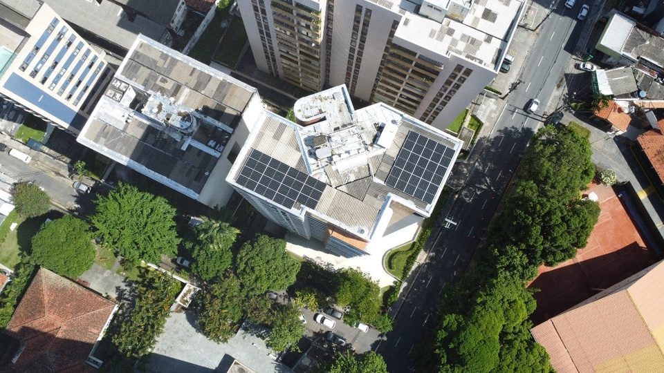 Vista aérea de conjunto de prédios arborizado com painéis solares nas lajes
